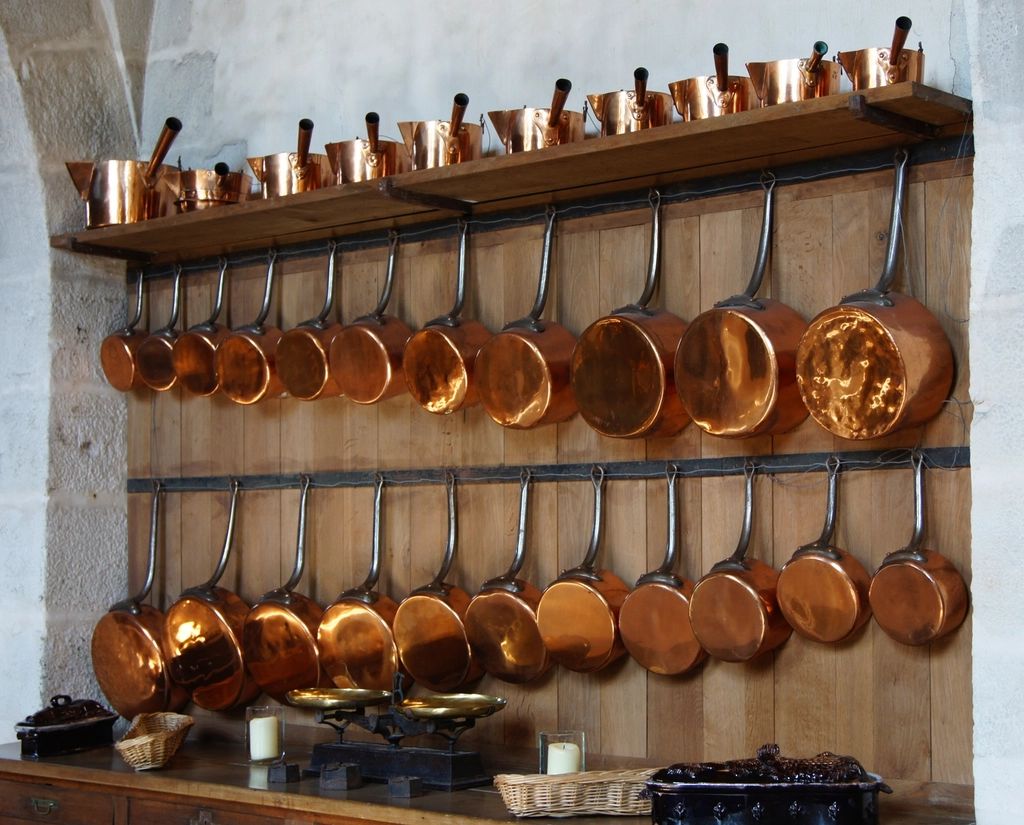 Styled photograph of a collection of polished copper saucepans in a kitchen